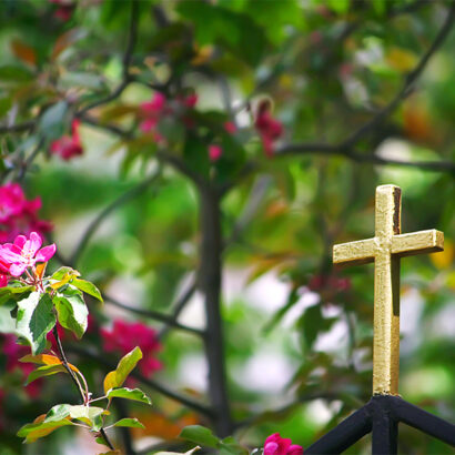Golden cross on the church fence, flowers of the apple tree, Easter composition, selective focus